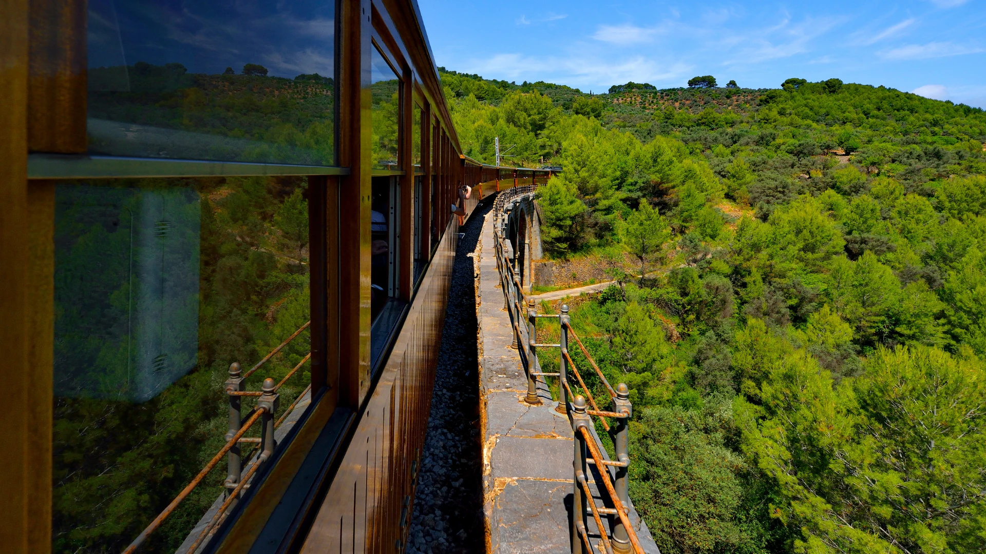 Vintage wooden train winding through orange groves in the Sóller valley — Belle Époque railway nostalgia, near our art retreat