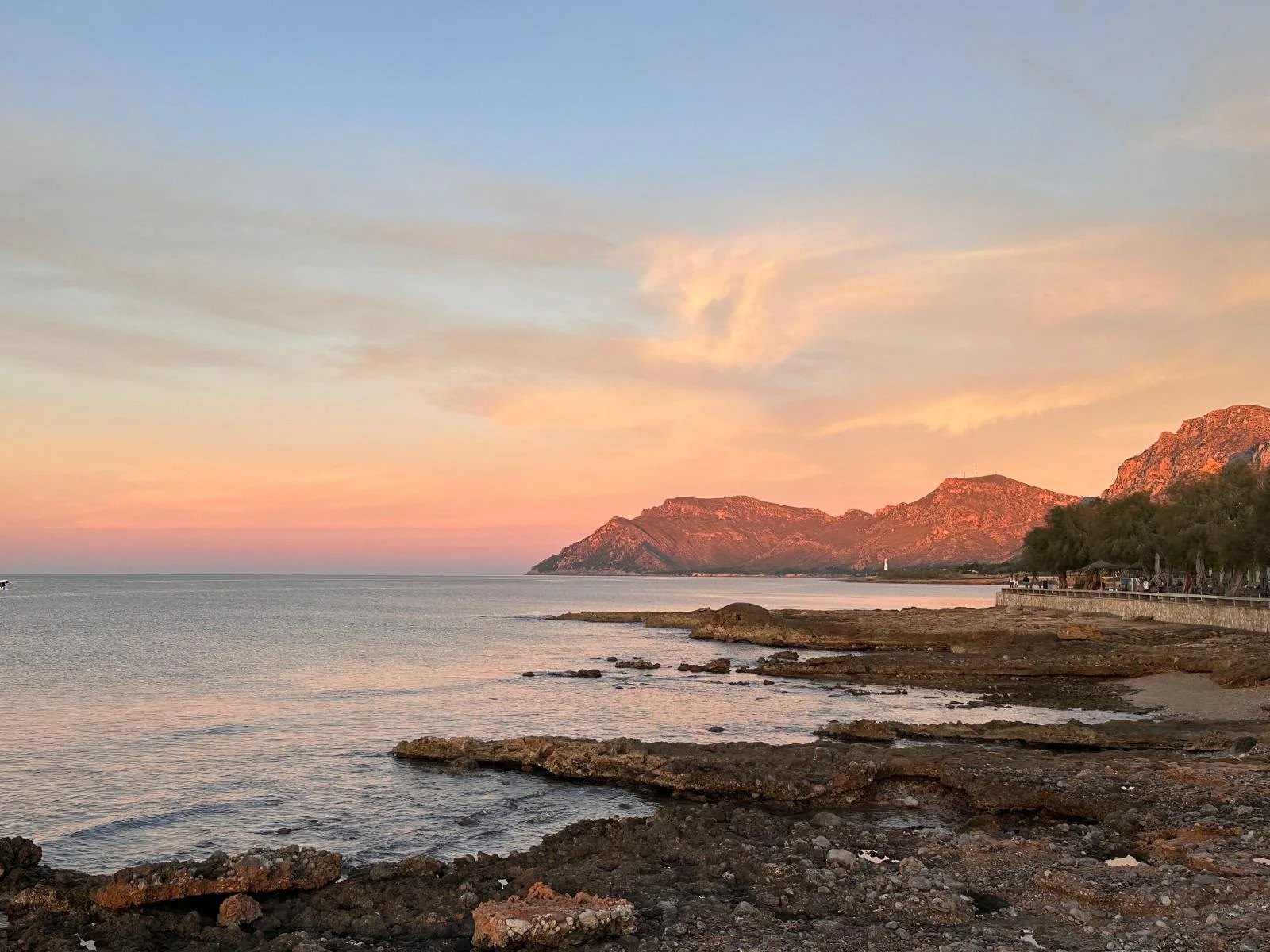 Sunset over the bay near Finca Es Cabàs — the Tramuntana slopes catching the last pink light as the sea goes still