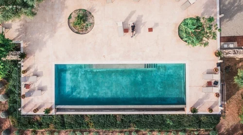 The pool at MALLORCA ART RETREAT — stone terrace, suites behind, mountains in the distance