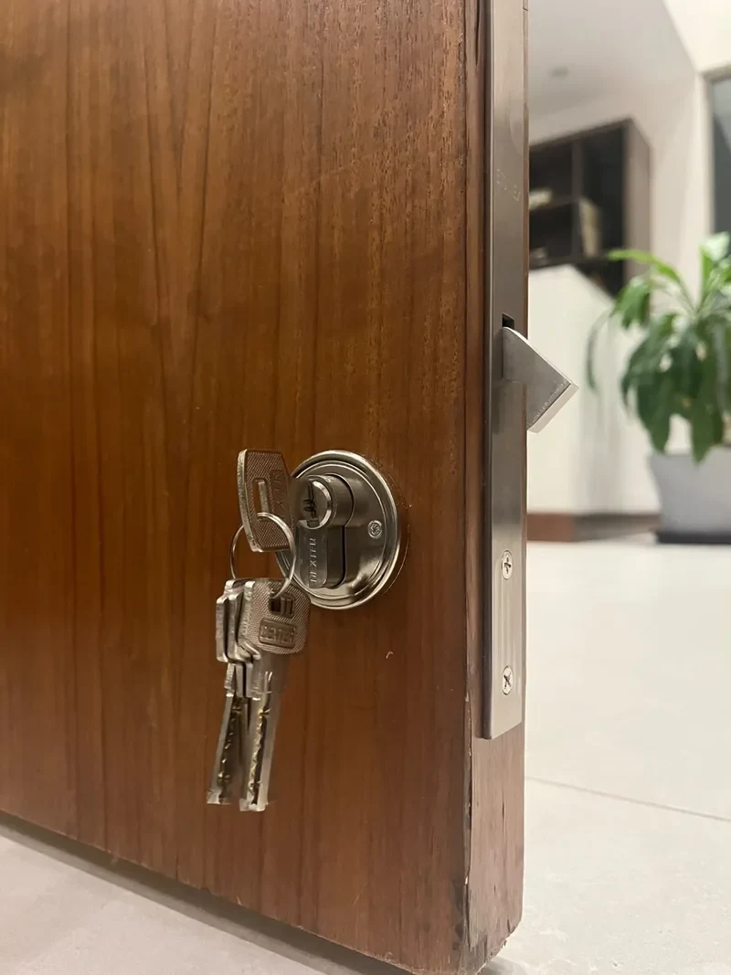 Cilindro de seguridad con llaves en una puerta de madera y pestillo metálico en el canto