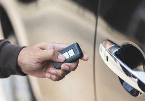 Mano sosteniendo un control de llave frente a la manija cromada de un automóvil