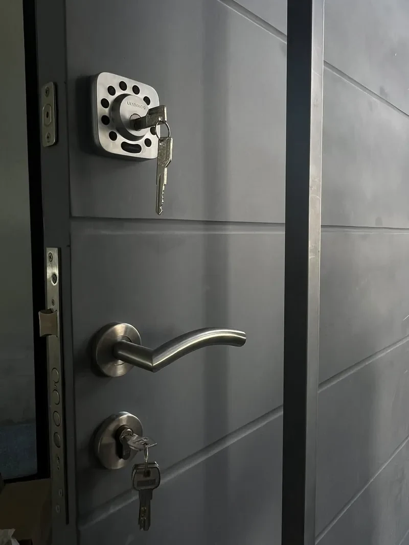 Puerta gris con cerradura de seguridad y manija de acero, con llaves insertadas