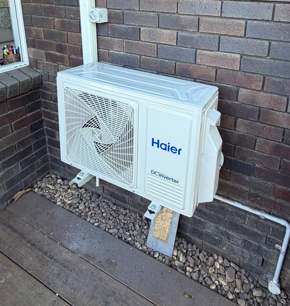 Haier split-system air conditioning outdoor unit newly installed on exterior wall of a Queensland home with Bailey ladders