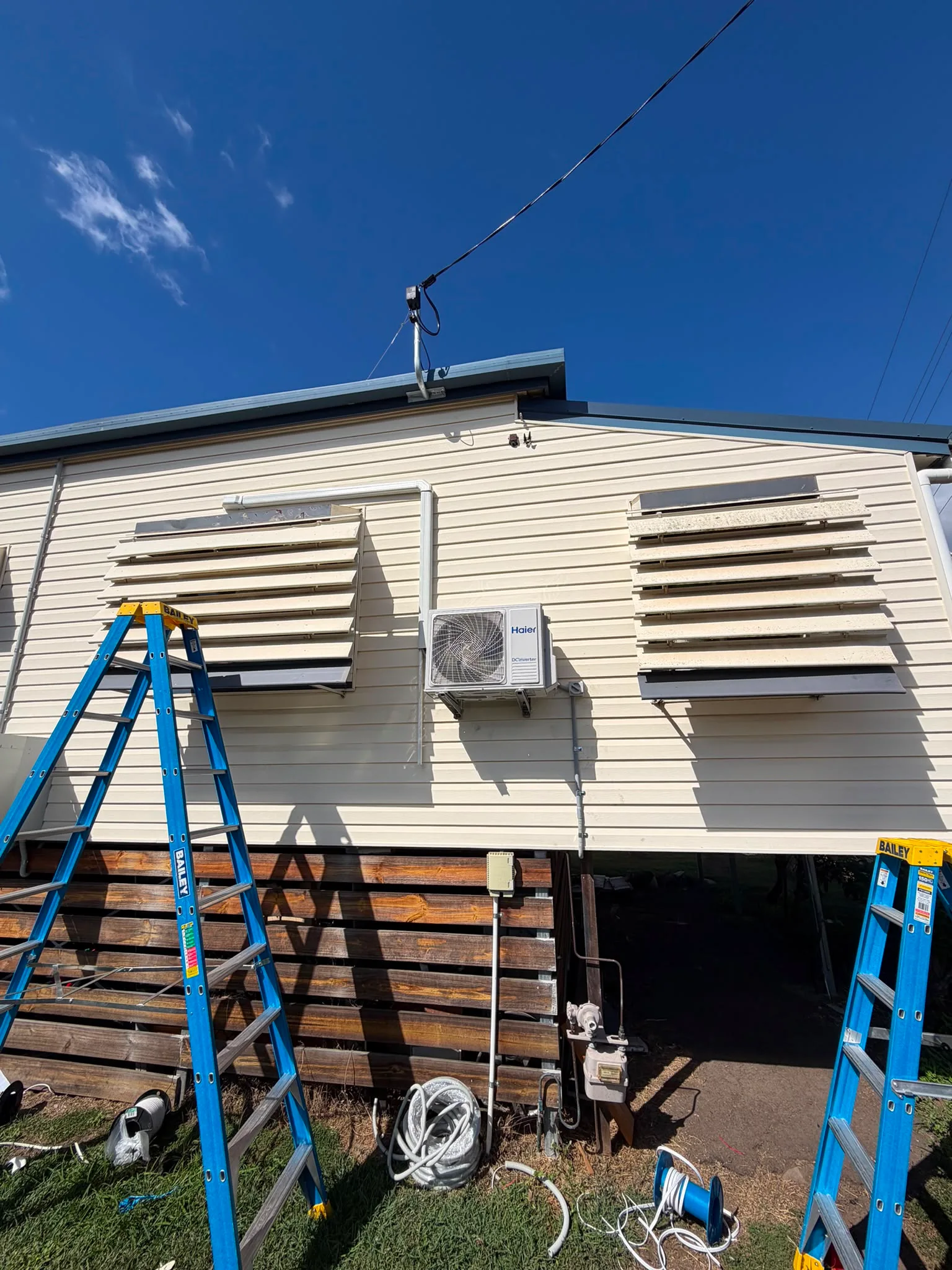 Split-system outdoor unit installed on a cream rendered wall of a Queensland home